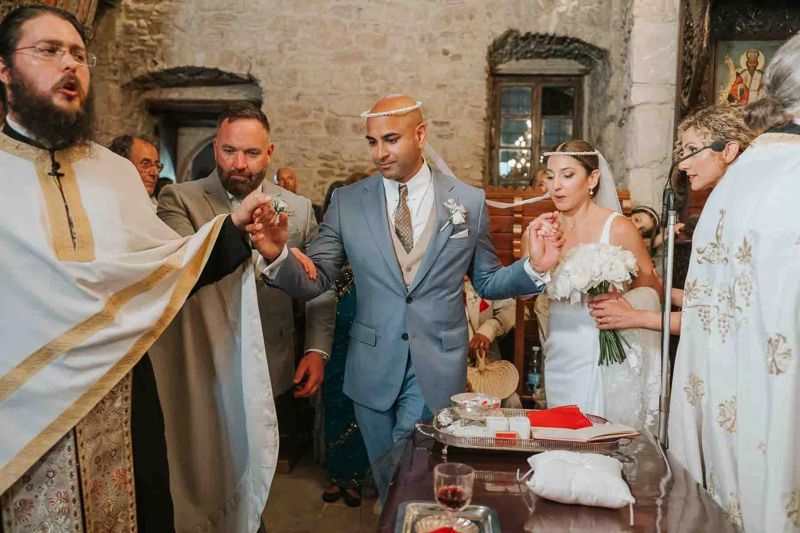  Bride and groom joined by their koumbaro as they perform the ceremonial walk around the altar during a Greek Orthodox wedding ceremony. 