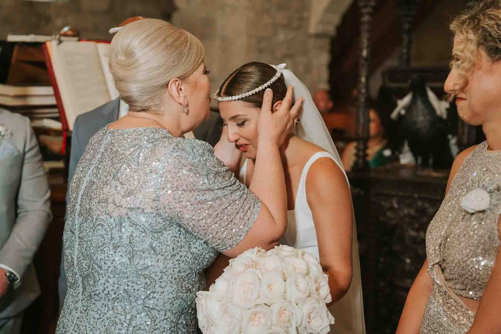  Mother adjusting the bride’s stefana crown during an emotional moment in a traditional Greek Orthodox wedding service. 