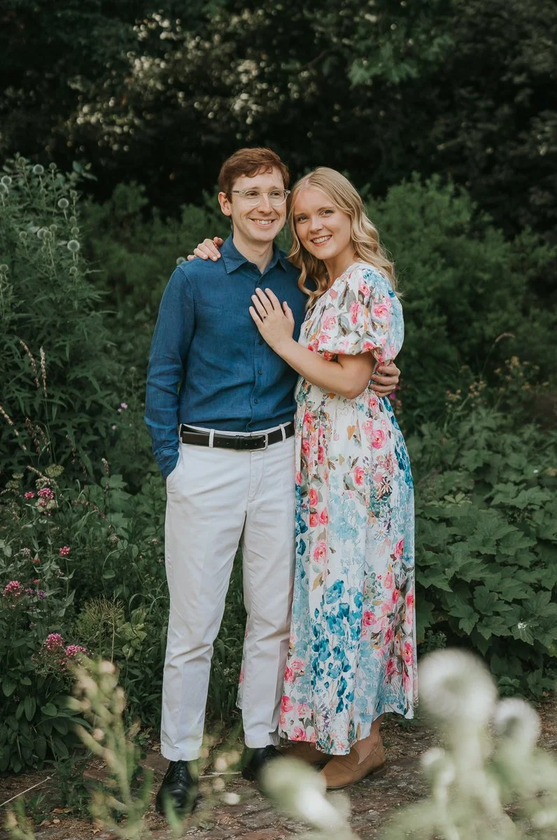  Natural engagement portrait session in Battersea Park, London, featuring a smiling couple surrounded by wildflowers and lush greenery in the park's beautiful gardens. 