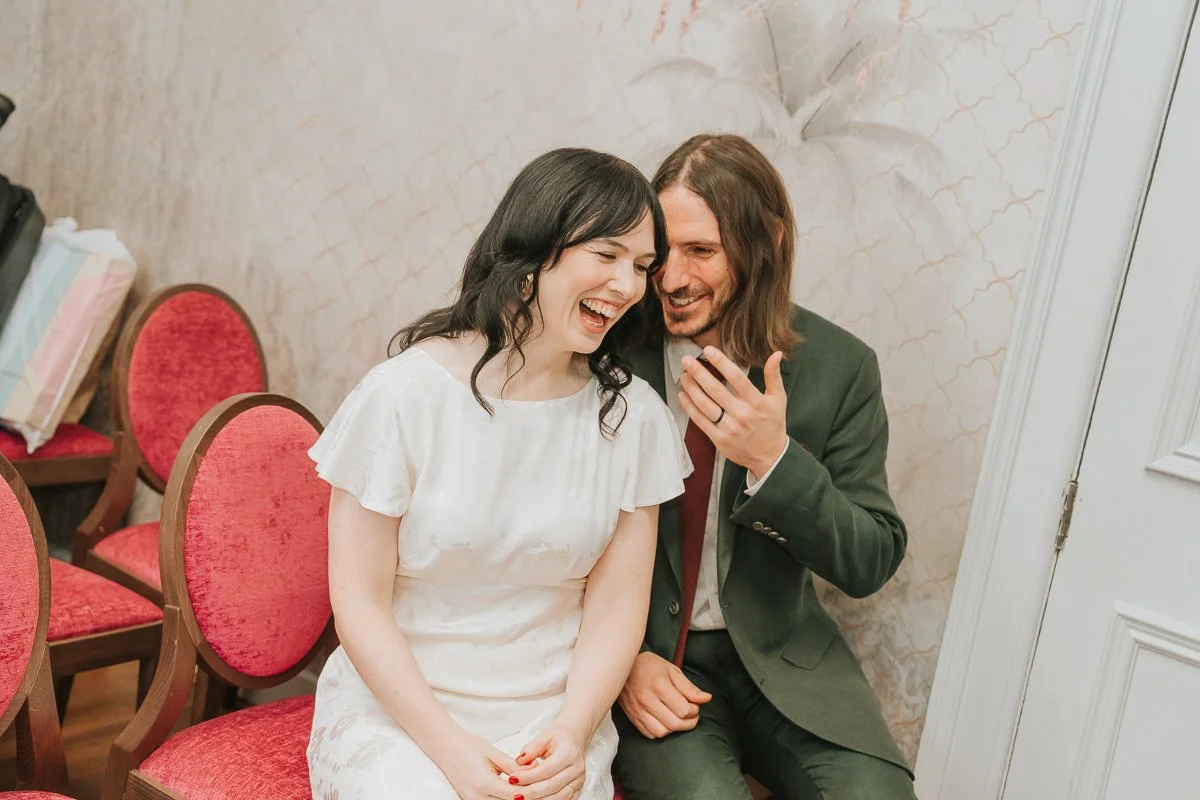  Bride and groom laughing together moments after their wedding ceremony in the  Pauline Room at Lambeth Town Hall , capturing a relaxed and candid documentary wedding moment. 