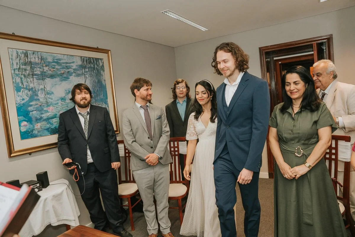  Bride and groom walking into their wedding ceremony at Kingston Register Office surrounded by smiling family and friends. 