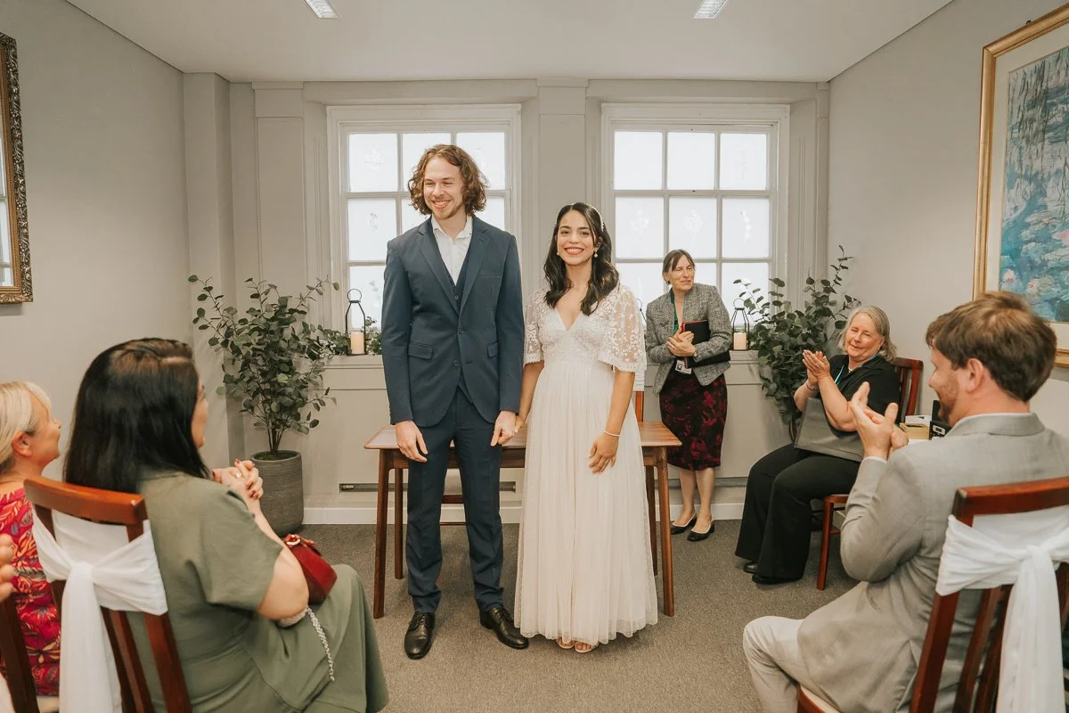  Newly married couple holding hands as guests applaud after their Kingston Register Office wedding ceremony. 