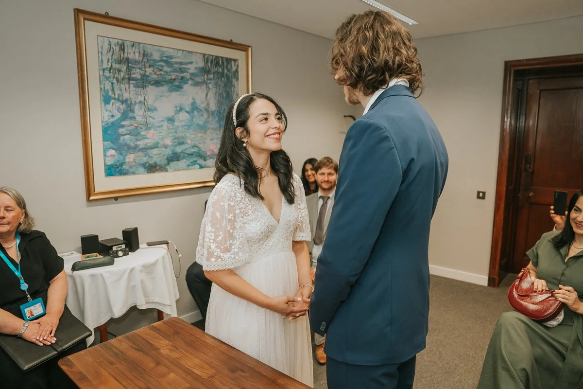  Bride and groom smiling at the registrar during their intimate wedding ceremony at Kingston Register Office in Surrey. 