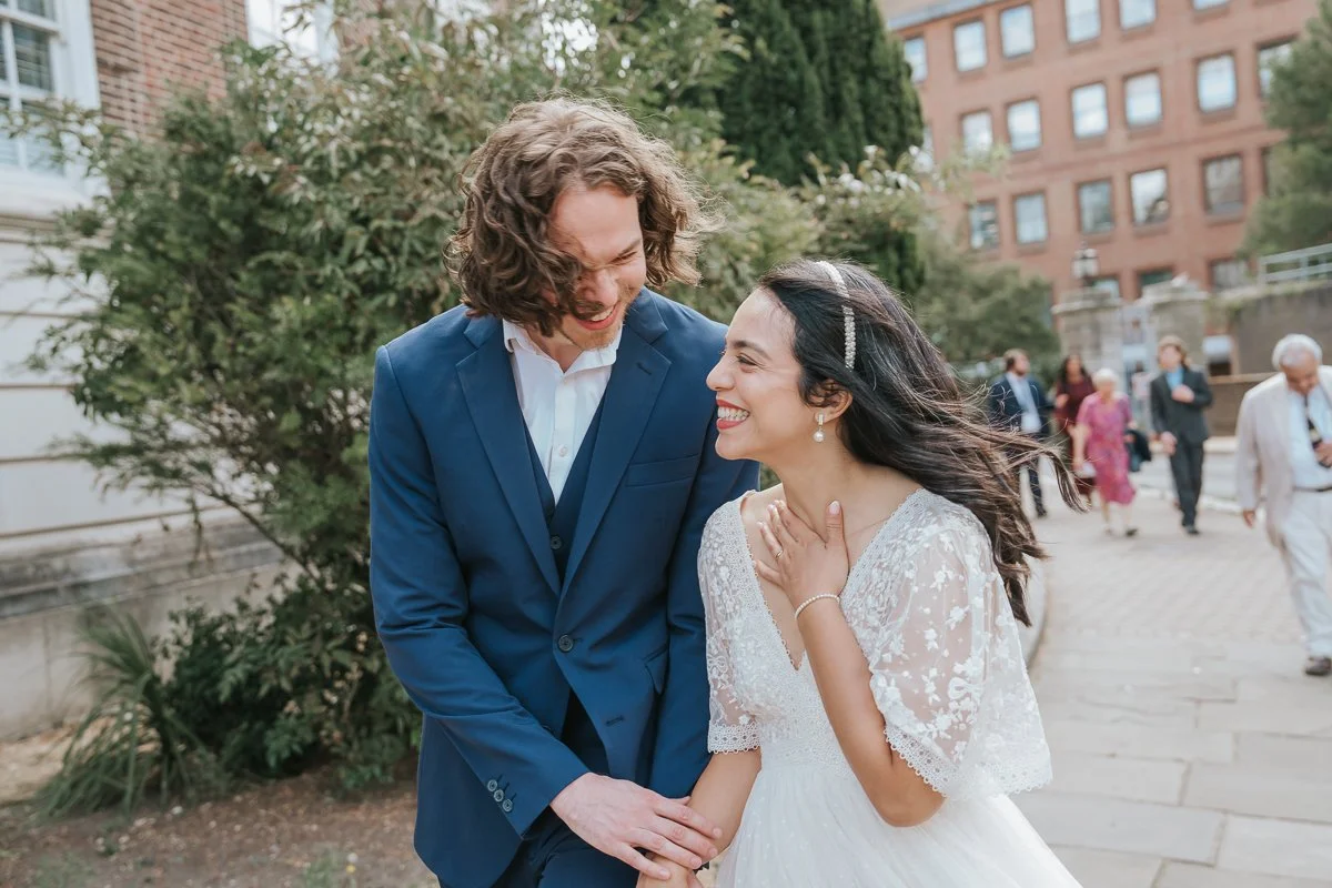  Natural wedding photography of the newly married couple walking hand in hand outside Kingston Register Office, sharing a joyful moment. 