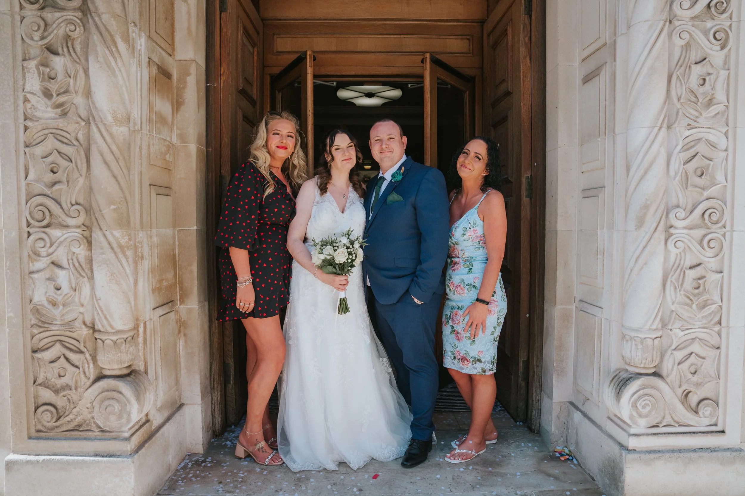  Bride and groom with two wedding guests posing in the ornate entrance doorway of Wandsworth Town Hall. 