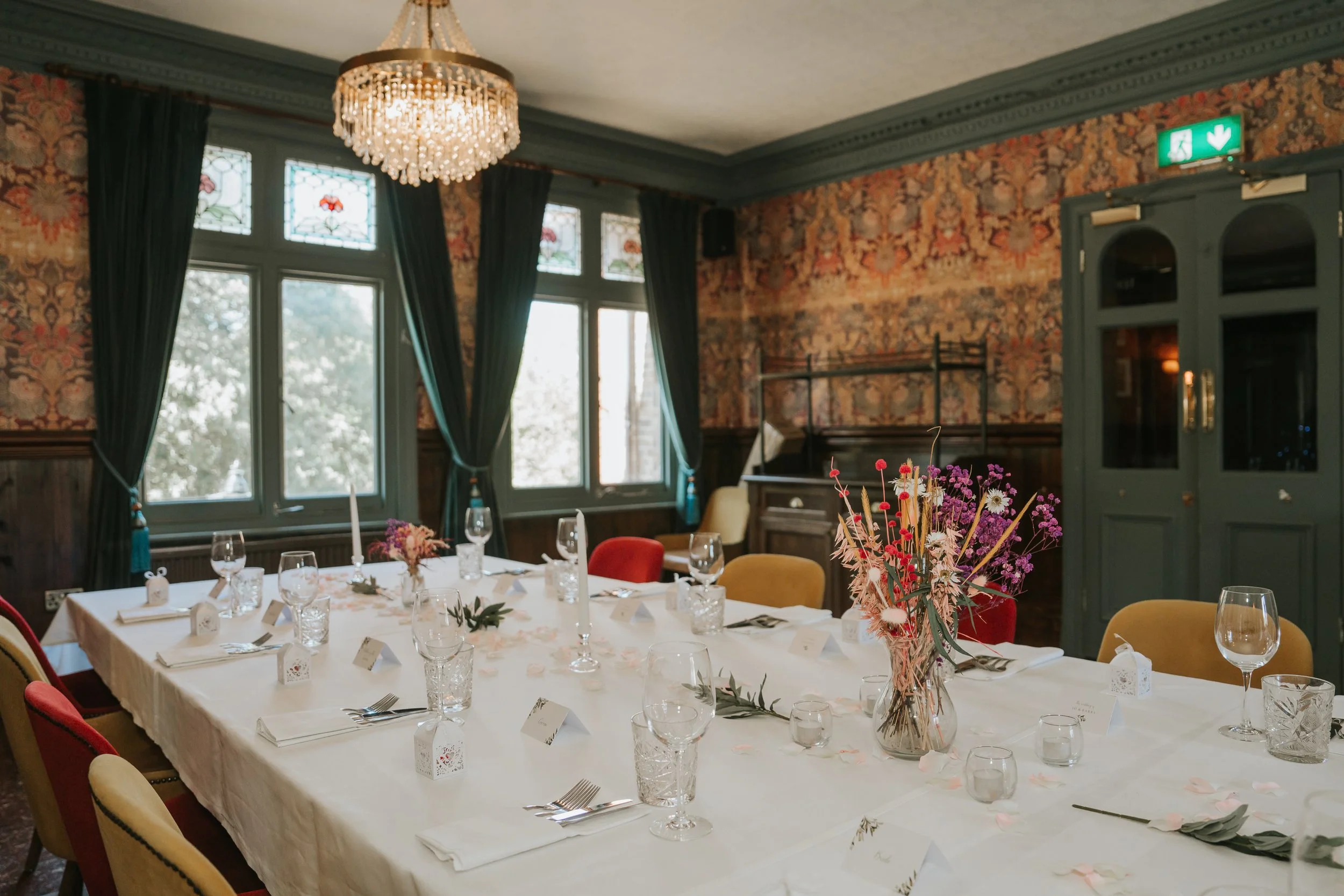  Wedding reception tables beneath a crystal chandelier and stained-glass windows in the Trinity Room at the County Arms pub. 