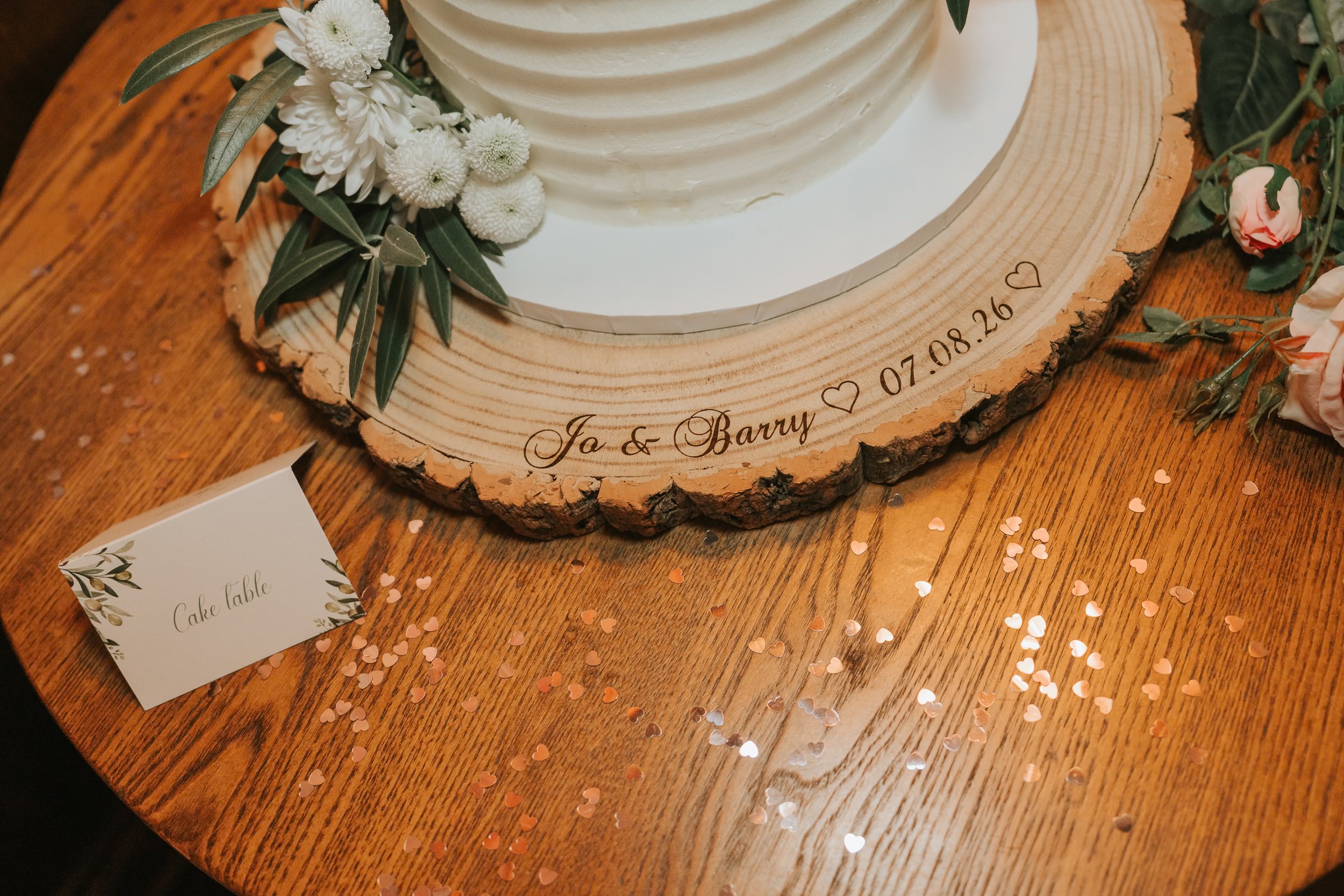  Personalised wooden wedding cake stand for Jo and Barry, surrounded by heart-shaped confetti at the County Arms. 