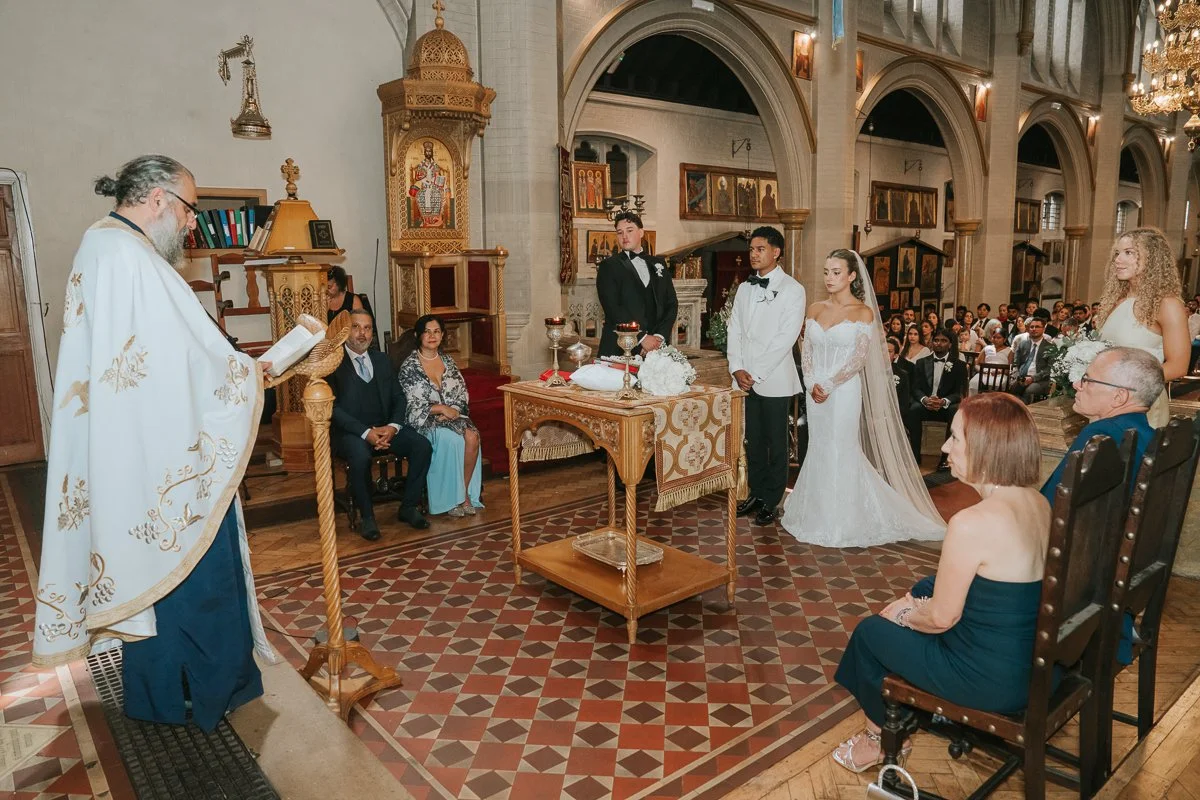  Greek Orthodox wedding ceremony at Saint Nectarios Church in Battersea, London, with the bride and groom before the priest. 