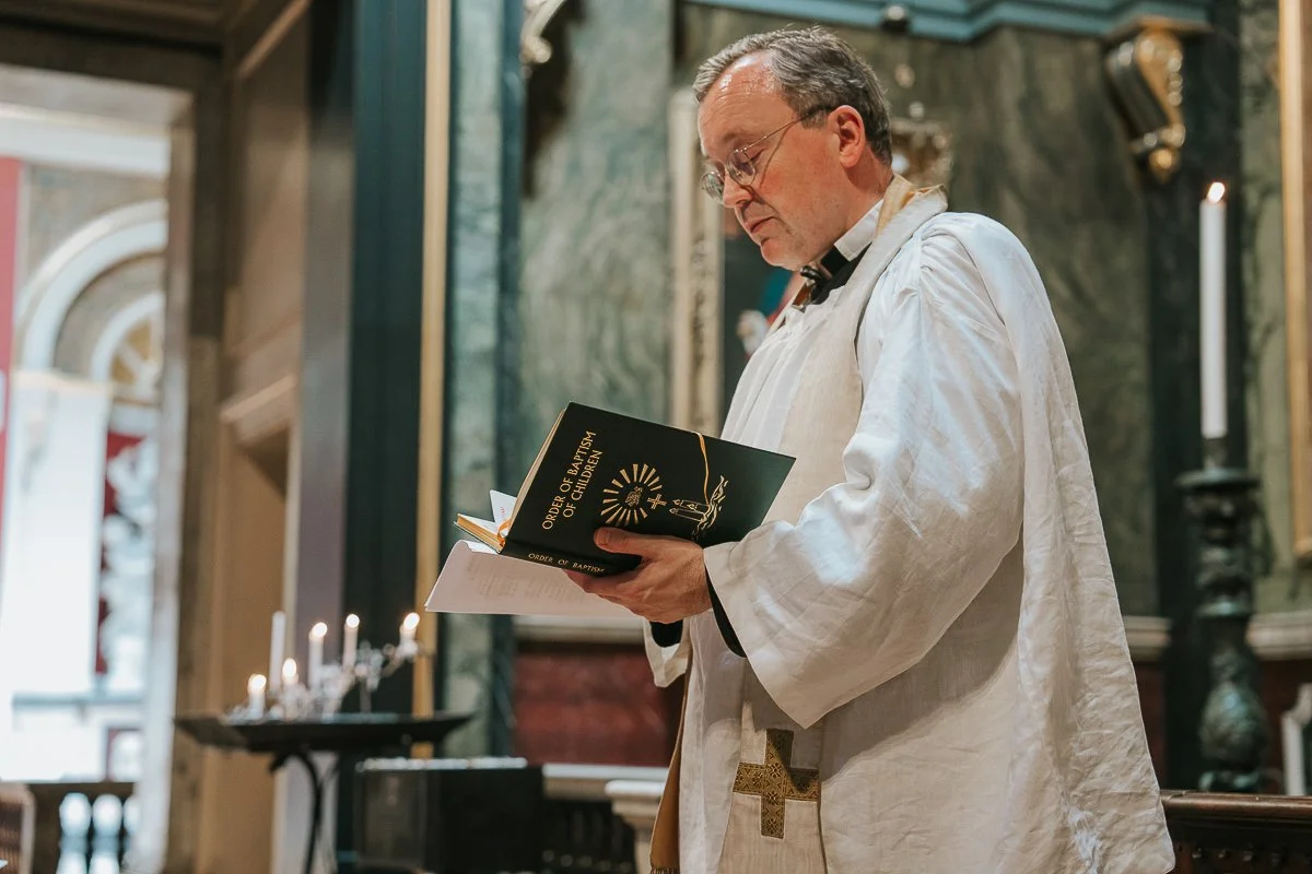  Priest preparing for a baby’s baptism at Brompton Oratory, holding the Order of Baptism of Children. 