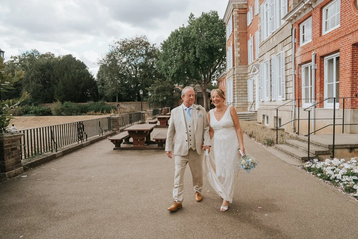  Newly married couple laughing together as they walk outside the historic York House in Twickenham after their wedding ceremony. 
