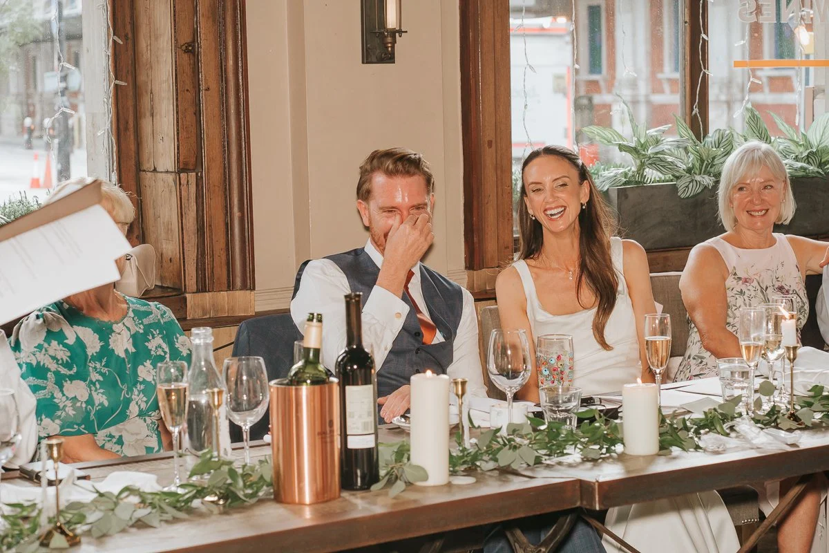  Bride and groom laughing during the speeches at their Balfour St Barts wedding reception in London. 