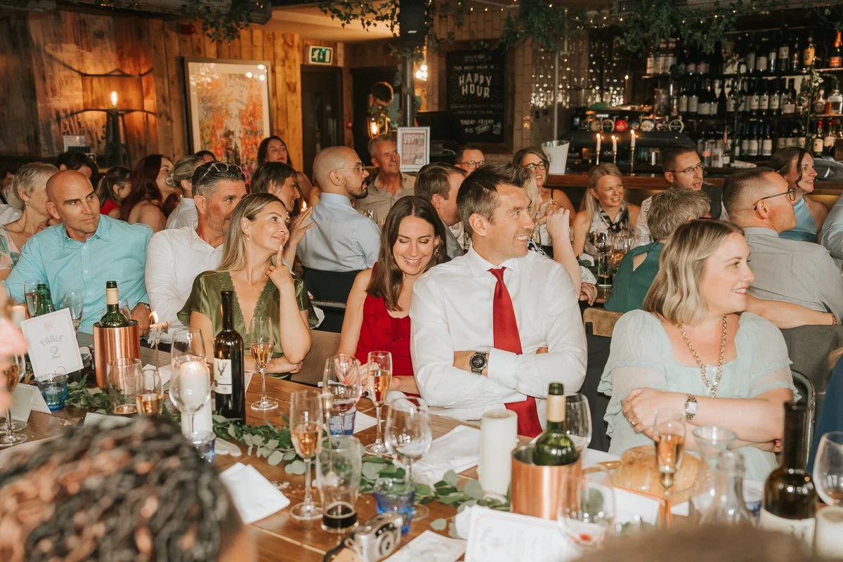  Wedding guests laughing during the speeches at a Balfour St Barts wedding reception in Smithfield, London. 