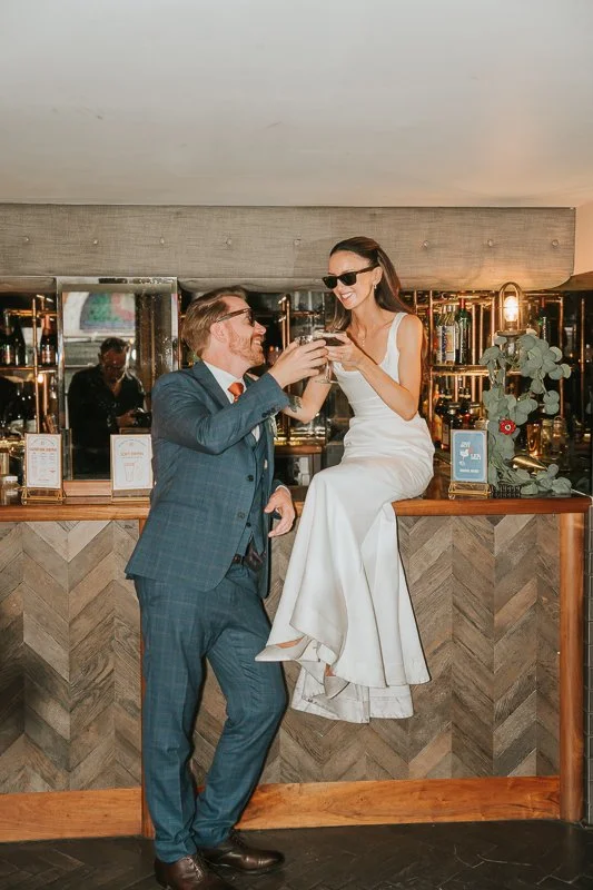  Newlyweds raising a toast at the bar during their wedding reception at Balfour St Barts in the City of London. 