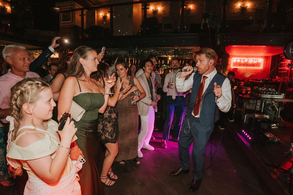  Groom singing with the live band as wedding guests dance at Balfour St Barts in Smithfield. 