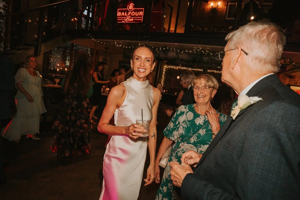  Bride chatting and laughing with family during her evening wedding reception at Balfour St Barts. 