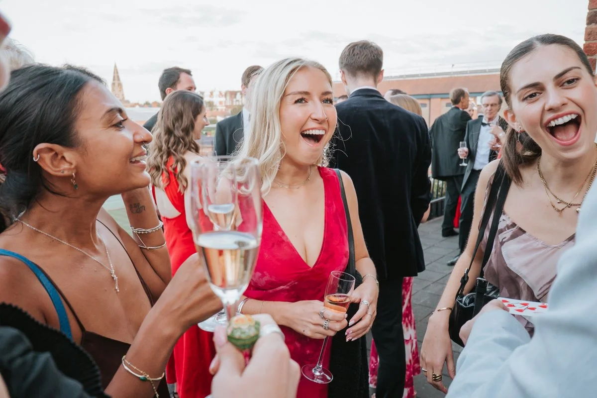  Friends chatting over drinks at an outdoor birthday reception at The Queen’s Club in West London. 