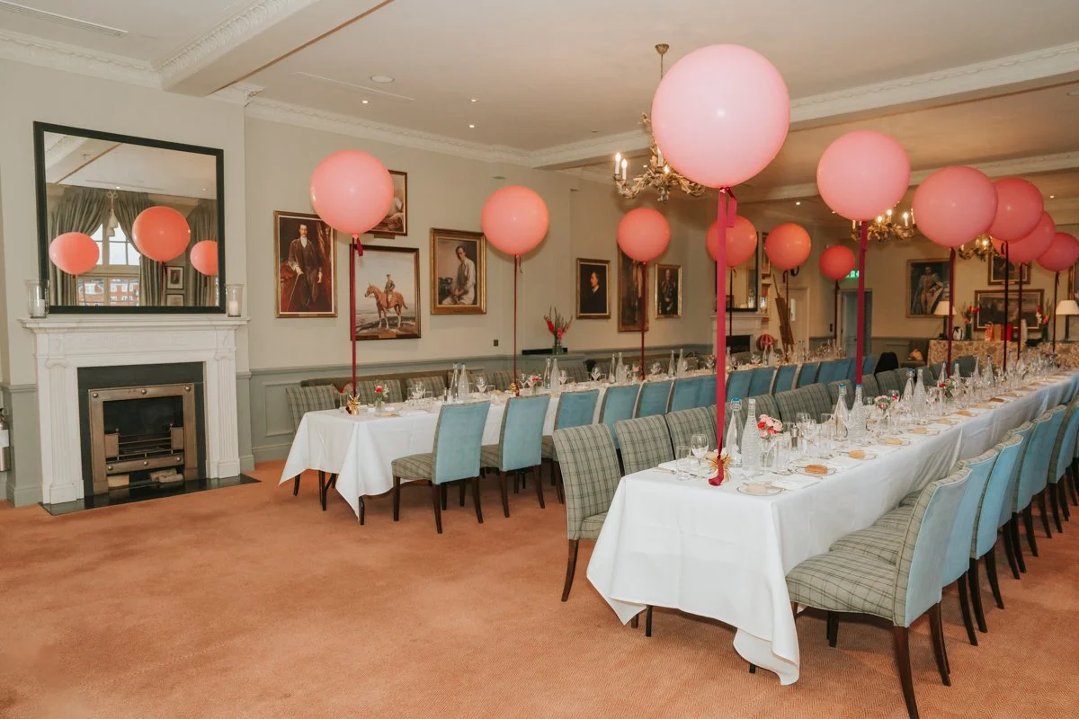  Elegant birthday dining area at The Queen’s Club in London, decorated with large pink balloons. 