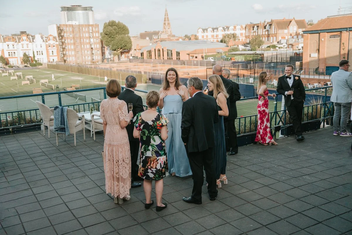  Guests enjoying cocktails on The Queen’s Club terrace overlooking its famous tennis courts. 
