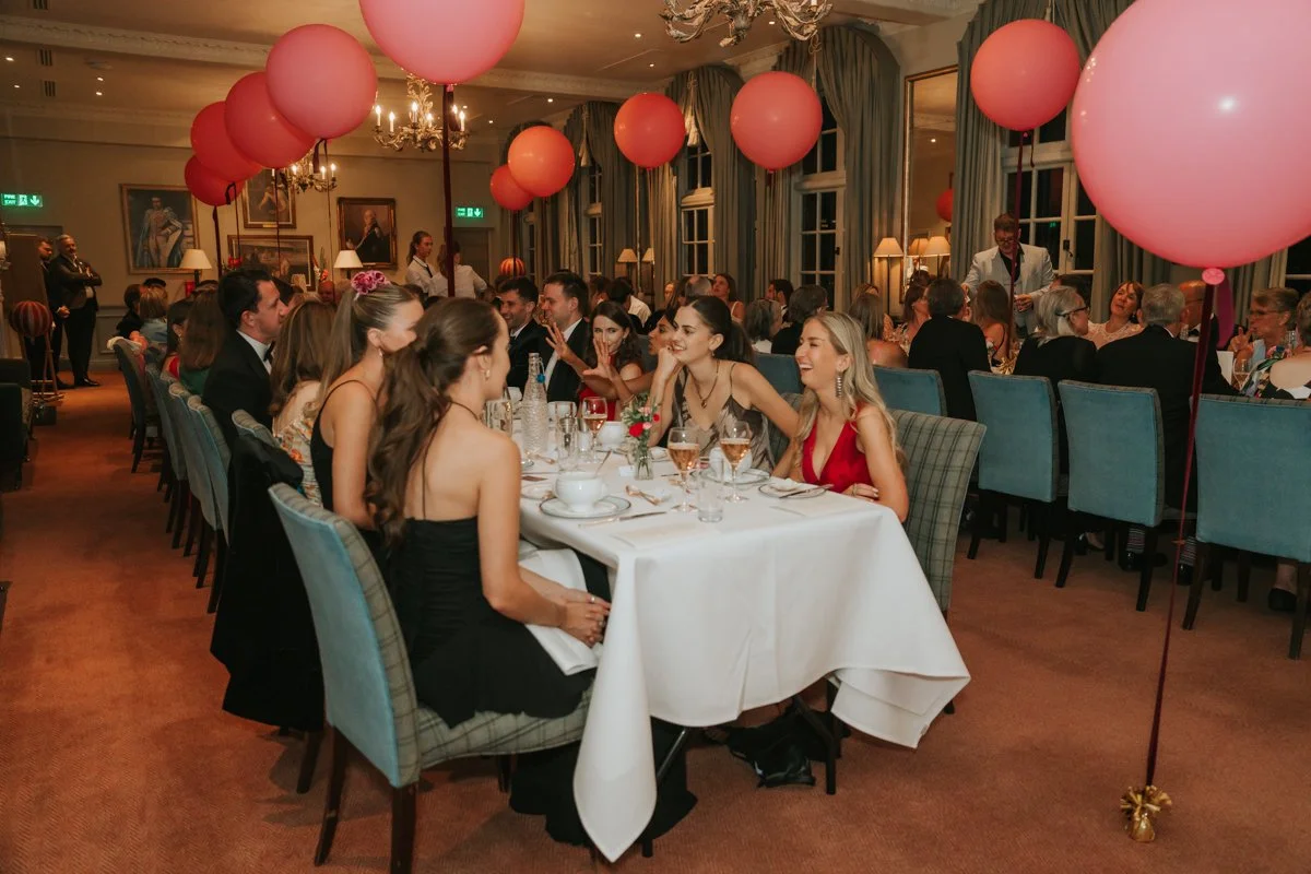  Guests dining beneath pink balloon decorations during a private 30th birthday celebration at The Queen’s Club. 