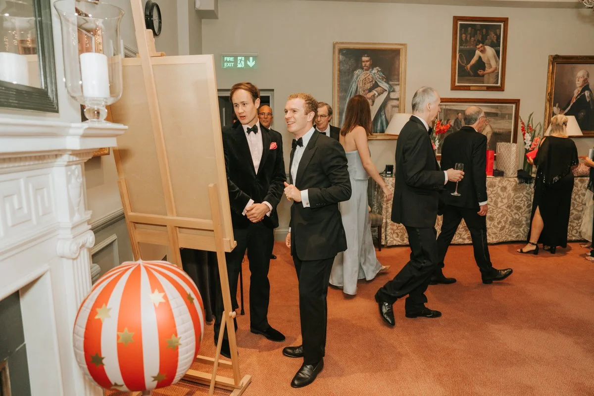  Guests gathering beside a photo display during a 30th birthday party at The Queen’s Club in London. 