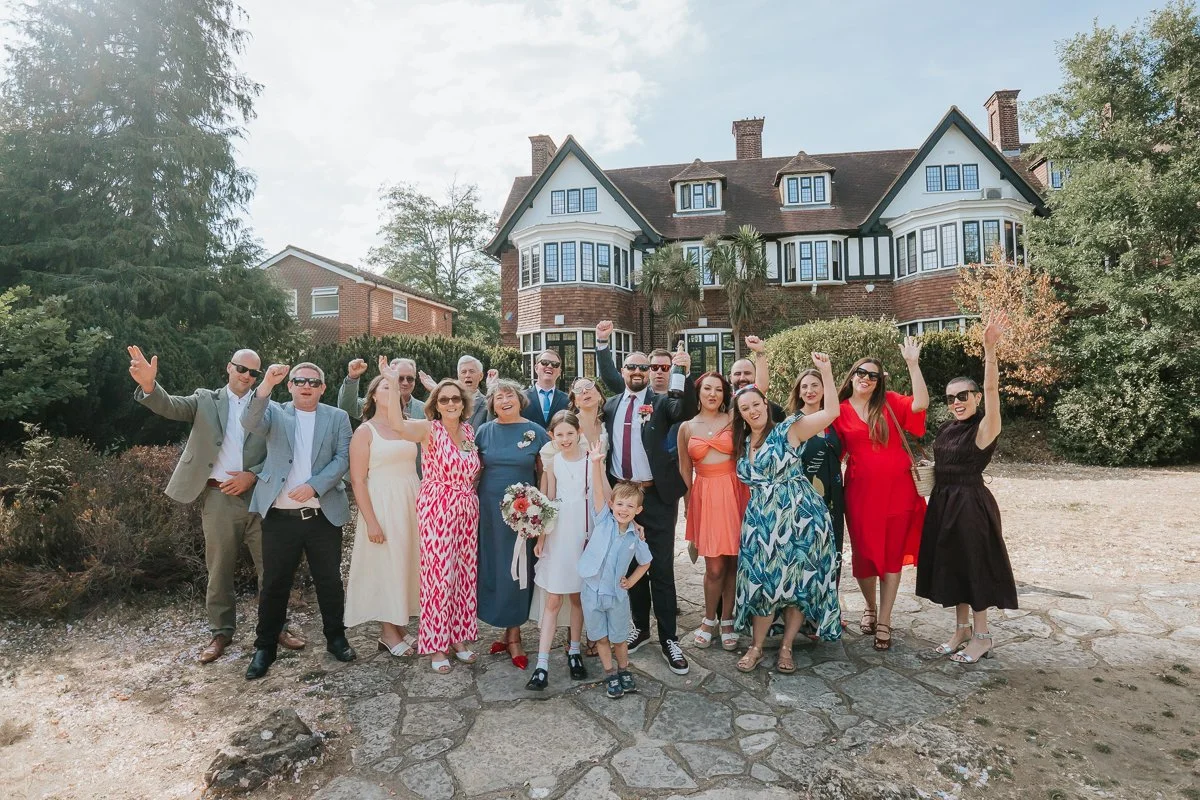  Weybridge Register Office wedding photography of the newlyweds cheering with family and friends outside the venue. 