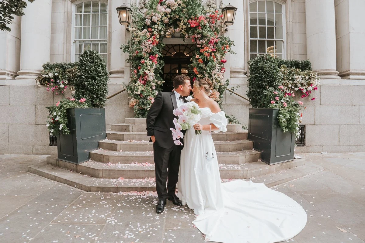  Chelsea Old Town Hall wedding photography of newlyweds kissing on the steps beneath the beautiful floral entrance. 
