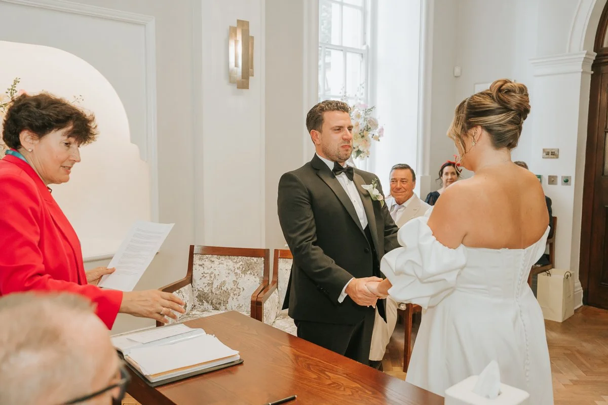  Bride and groom holding hands and exchanging vows while getting married in chelsea old town hall register office. 