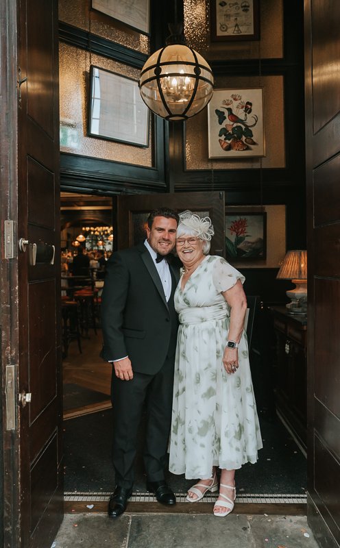  Groom laughing with a wedding guest at the entrance to The Trafalgar on the King’s Road. 