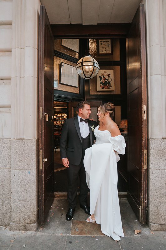  Bride and groom sharing a relaxed moment in the doorway of The Trafalgar pub following their Chelsea wedding. 