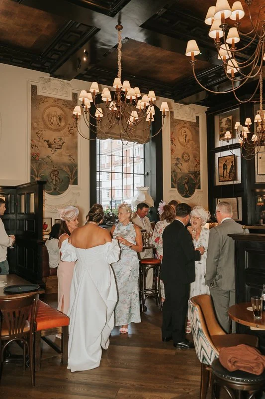  Bride mingling with guests beneath the chandeliers during her wedding reception at The Trafalgar 