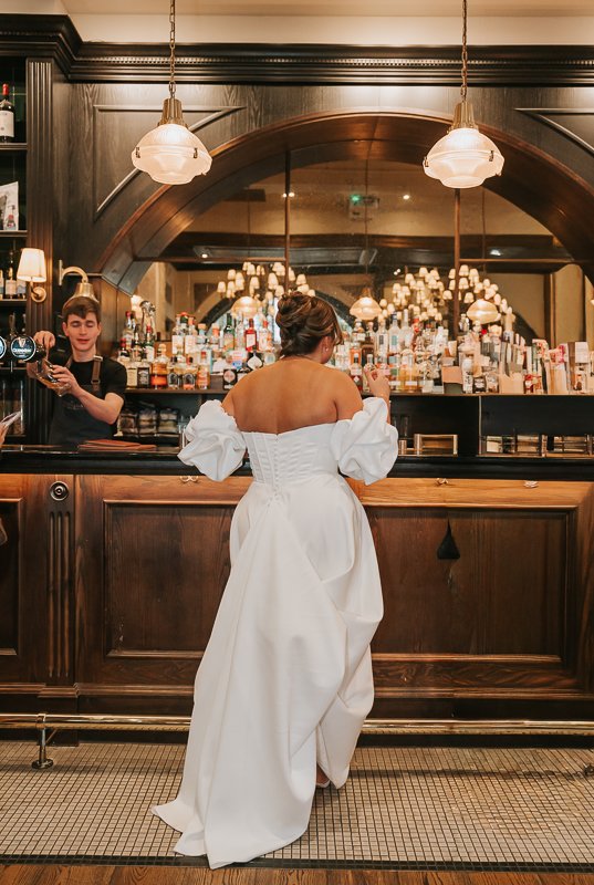  Bride ordering a drink at the elegant wooden bar inside The Trafalgar on the King’s Road. 