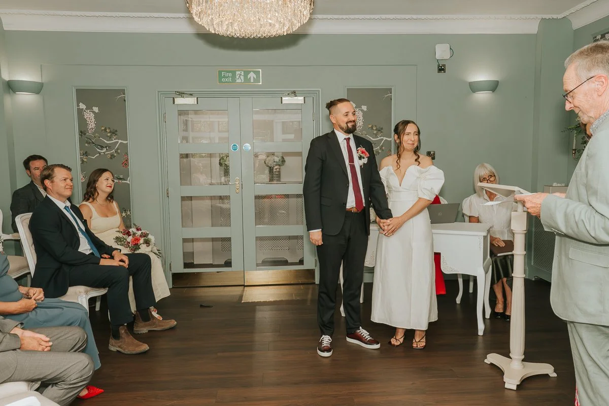  Weybridge Register Office wedding ceremony with the bride and groom standing together in front of their guests. 