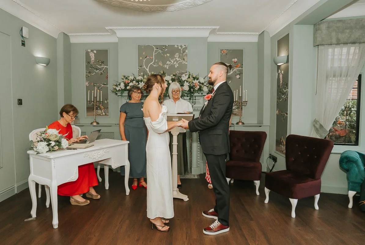  Couple holding hands during their intimate civil wedding ceremony at Weybridge Register Office in Surrey. 