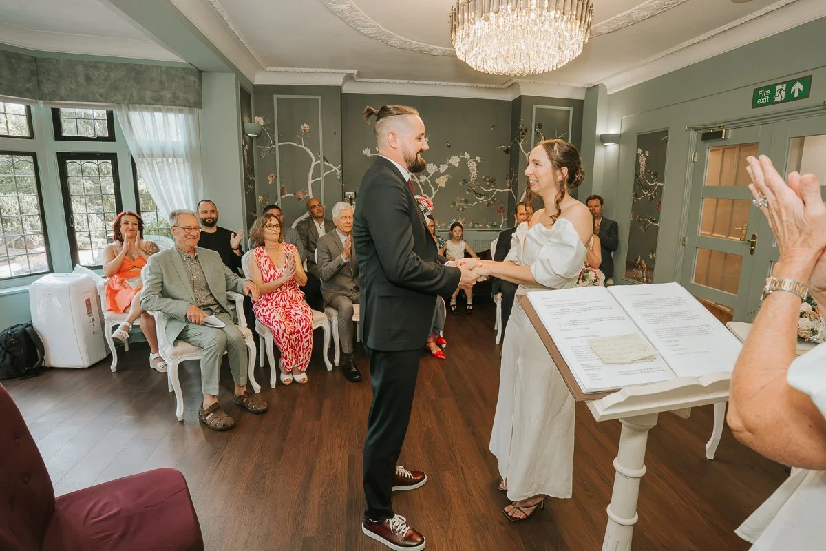  Bride and groom smiling at each other during their intimate civil ceremony at Weybridge Register Office. 