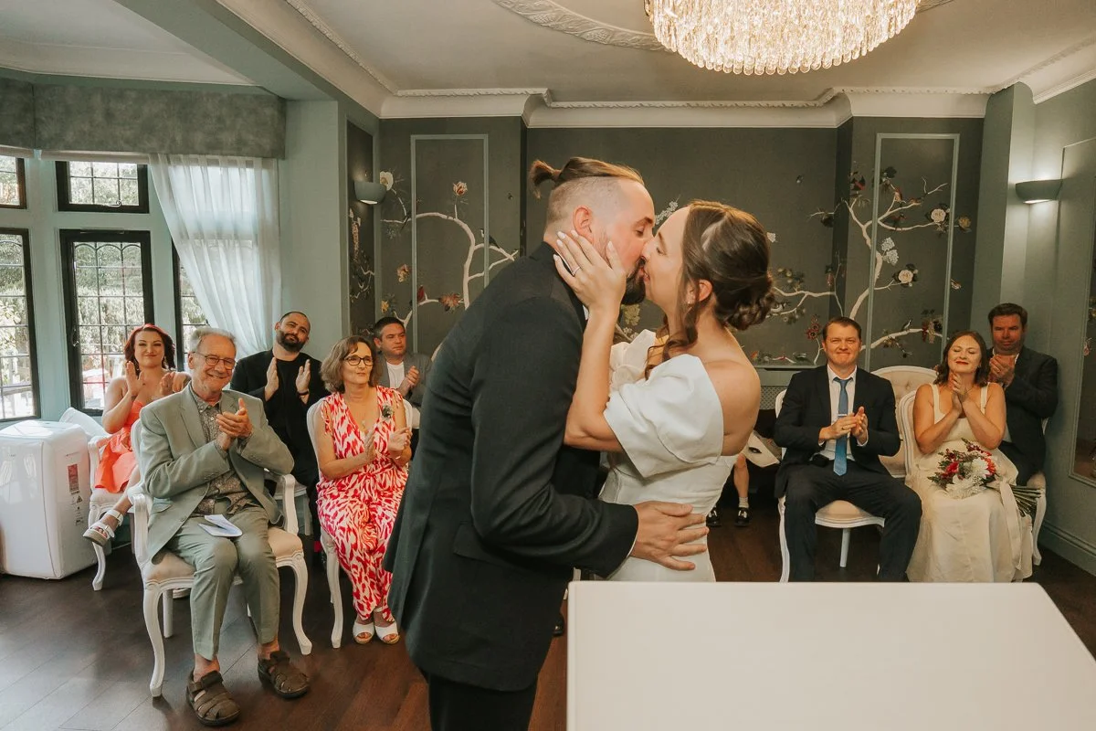  Bride and groom kissing as guests applaud during their Weybridge Register Office wedding ceremony. 
