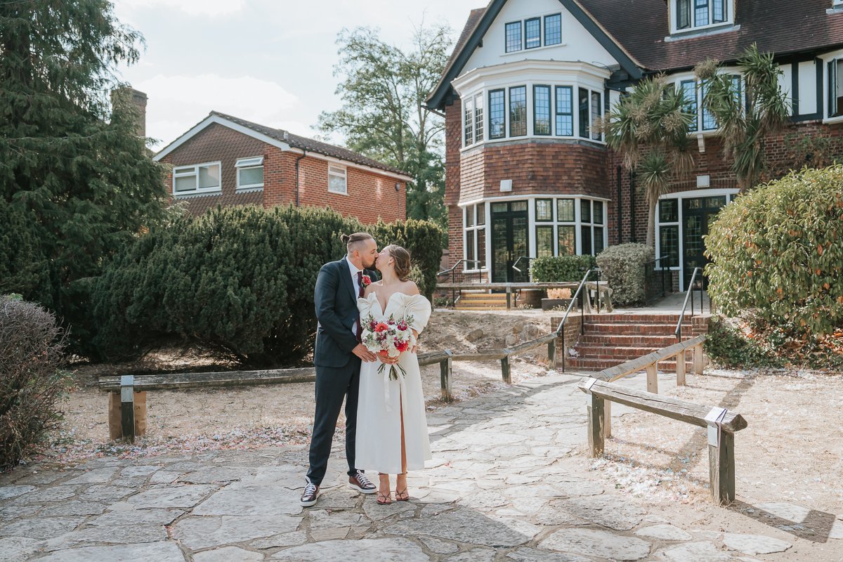  Bride and groom sharing a kiss in the gardens outside Weybridge Register Office after their wedding ceremony. 