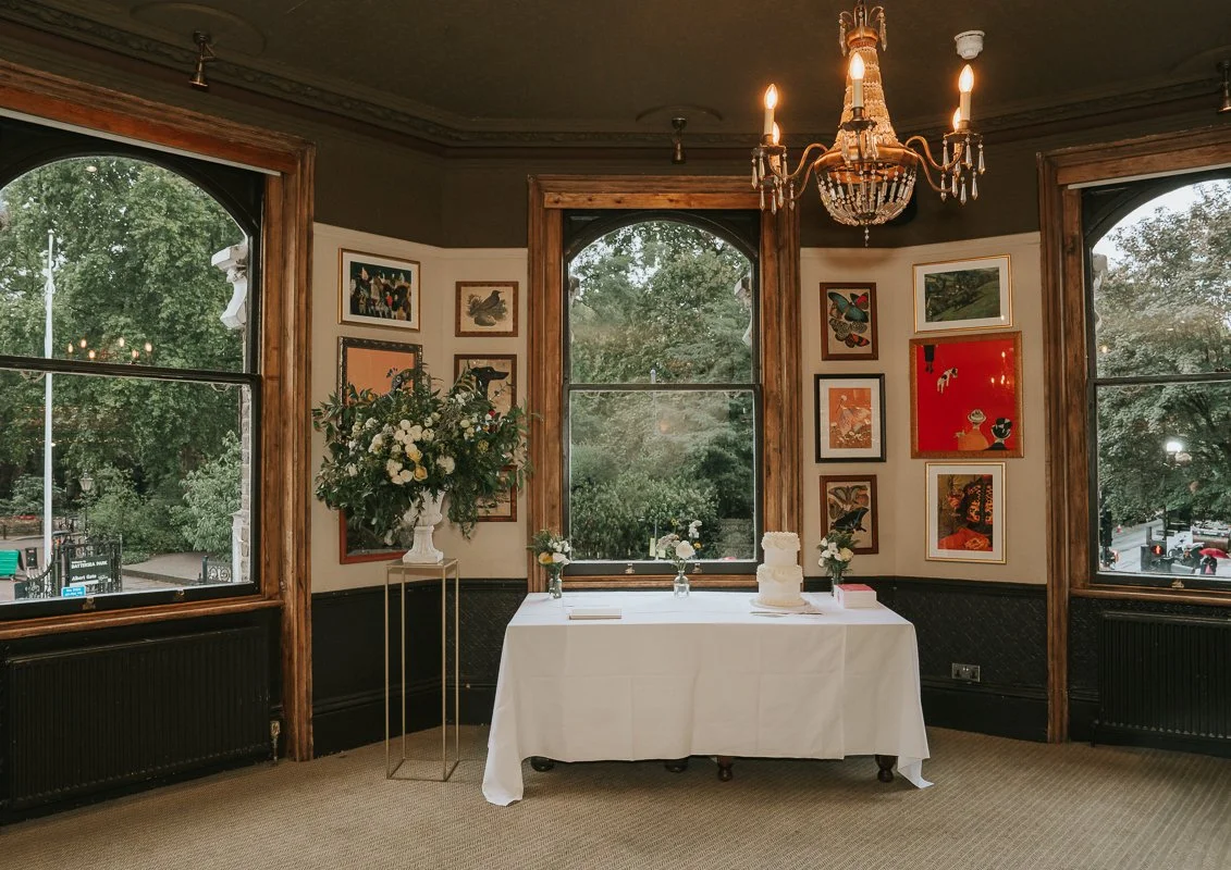  Wedding cake and flowers beside the arched windows in the Bridge Room at The Prince Albert, Battersea. 