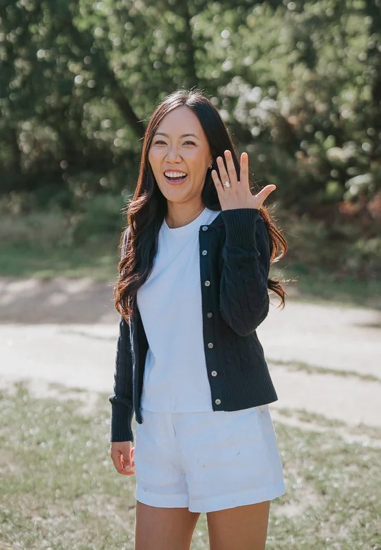  Smiling woman showing her engagement ring during a photoshoot in Isabella Plantation, Richmond Park. 