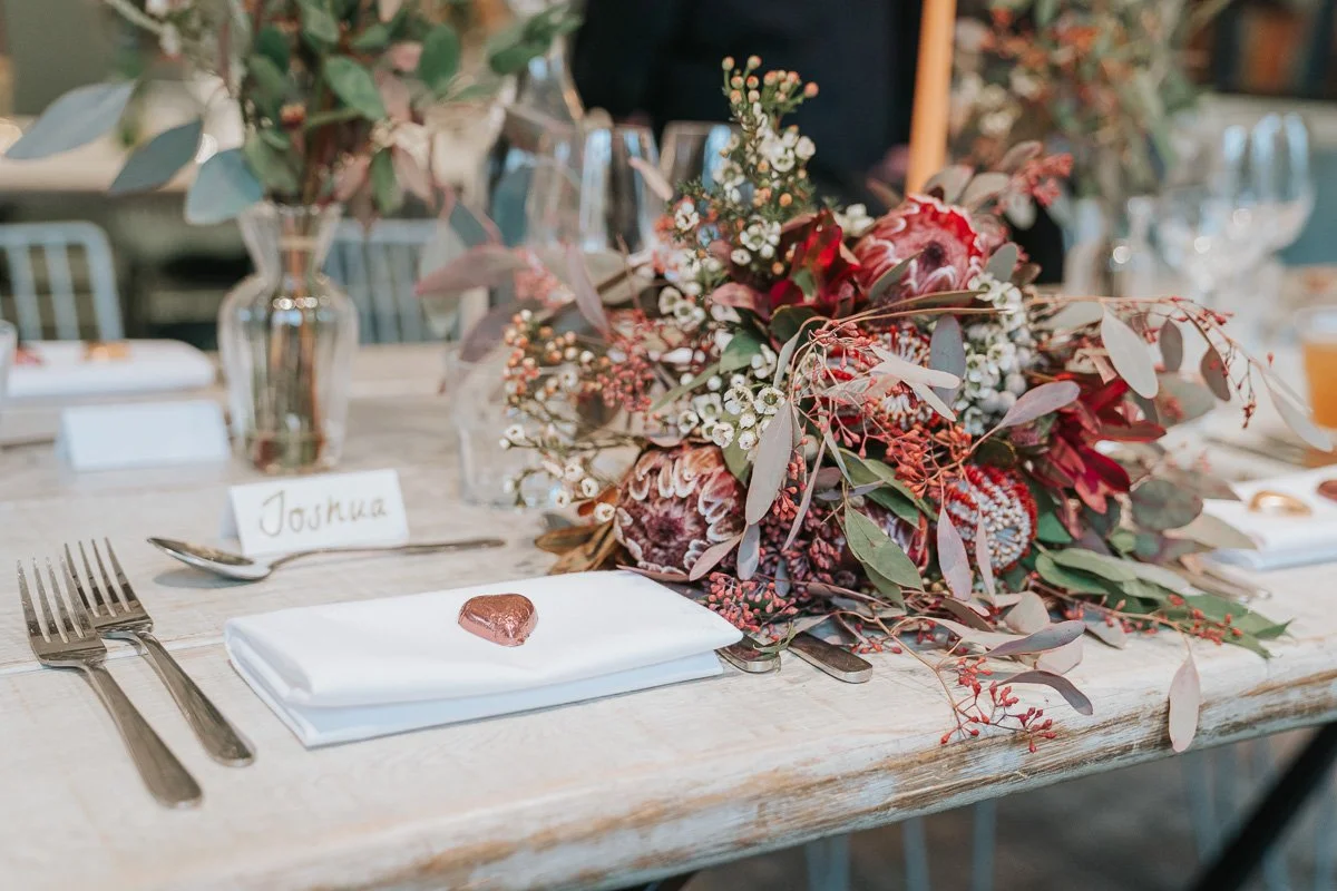  Wedding table at The Phene in Chelsea with a protea bouquet, eucalyptus and heart-shaped chocolate favours. 