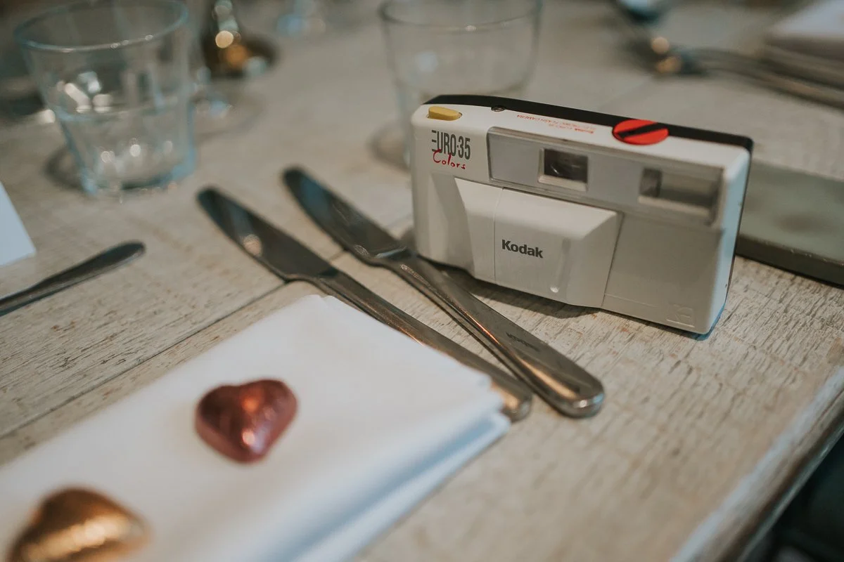    Kodak film camera beside chocolate heart favours on a wedding table at The Phene, Chelsea. 