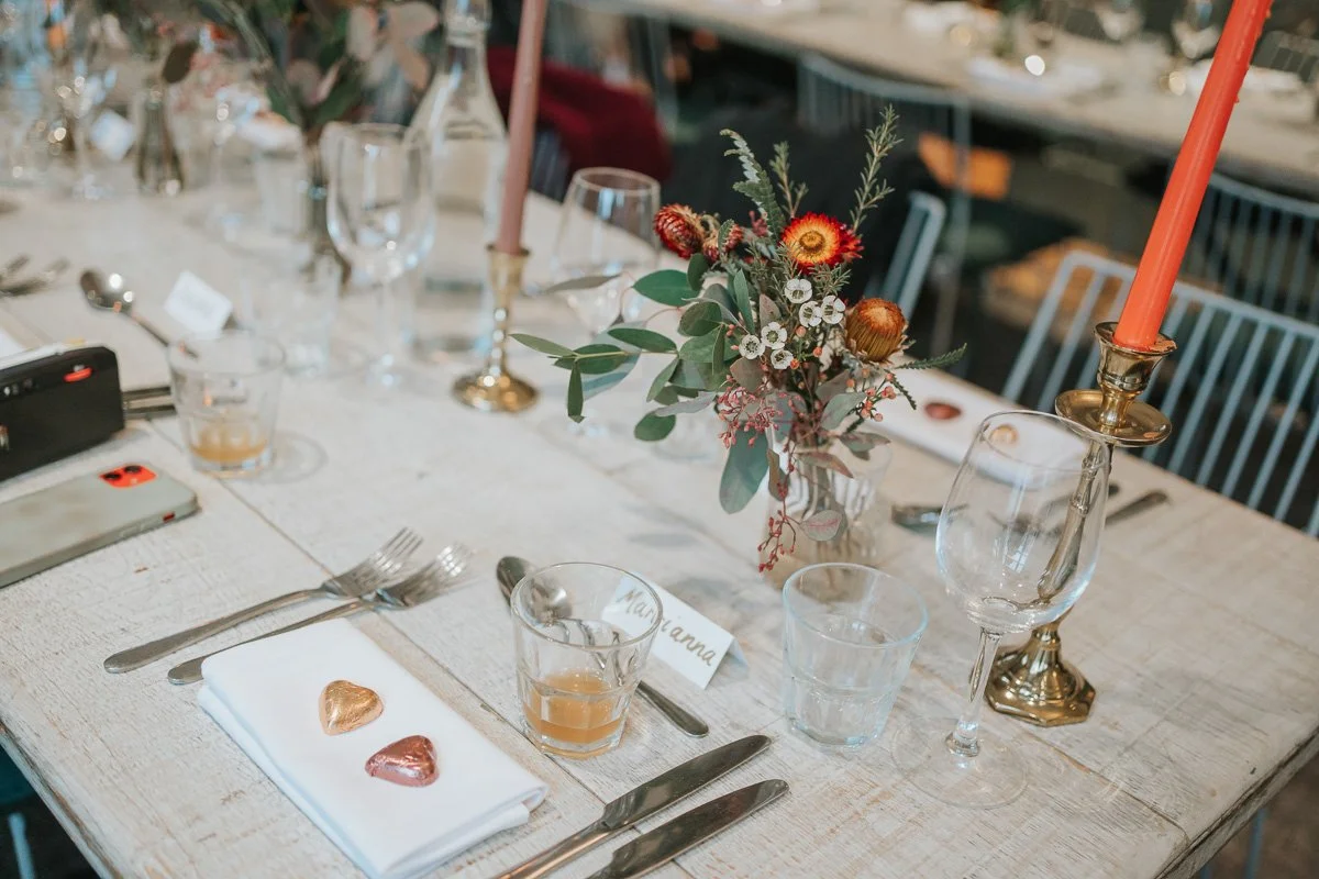  Wedding table at The Phene decorated with orange candles, colourful flowers and chocolate heart favours. 