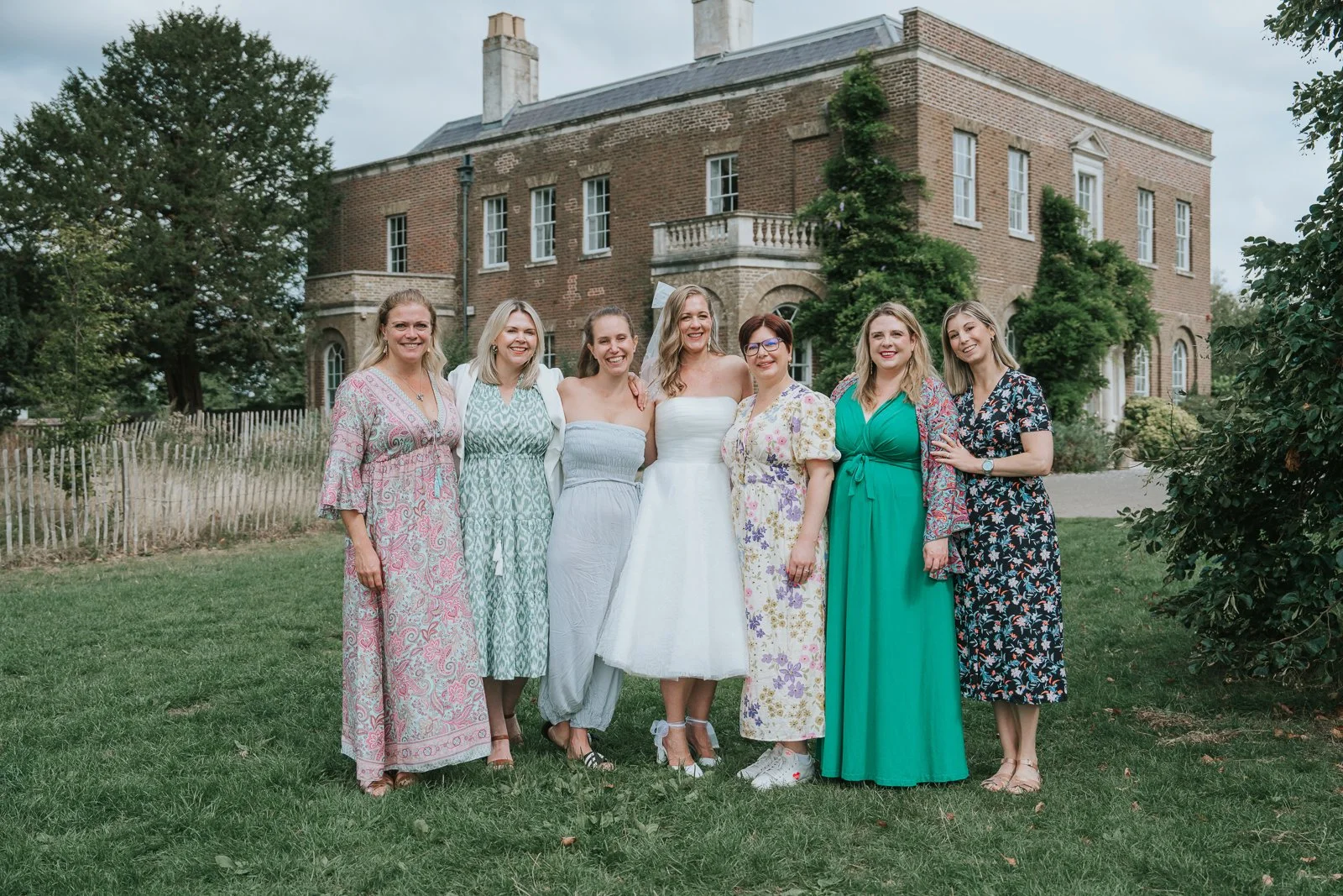  Bride with six wedding guests on the lawn outside Morden Park House. 