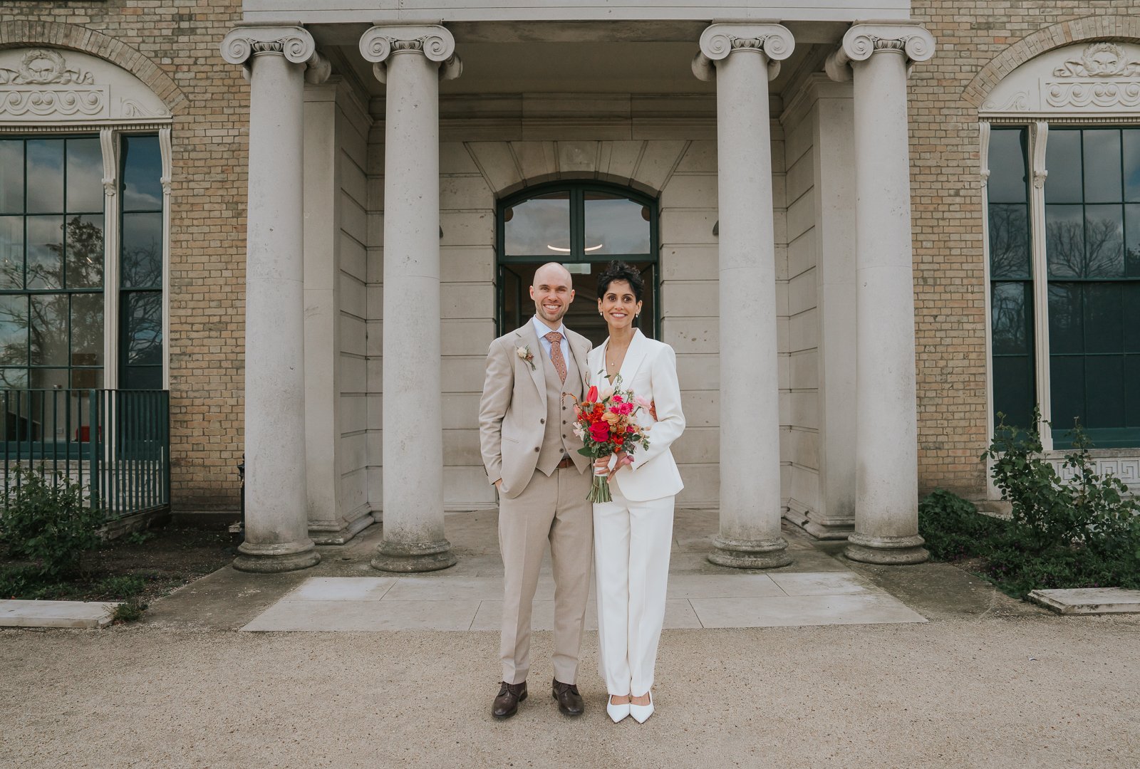 Bride and groom standing beneath the grand columns of Brockwell Hall in Brockwell Park, South London wedding venue, elegant civil ceremony couple portrait