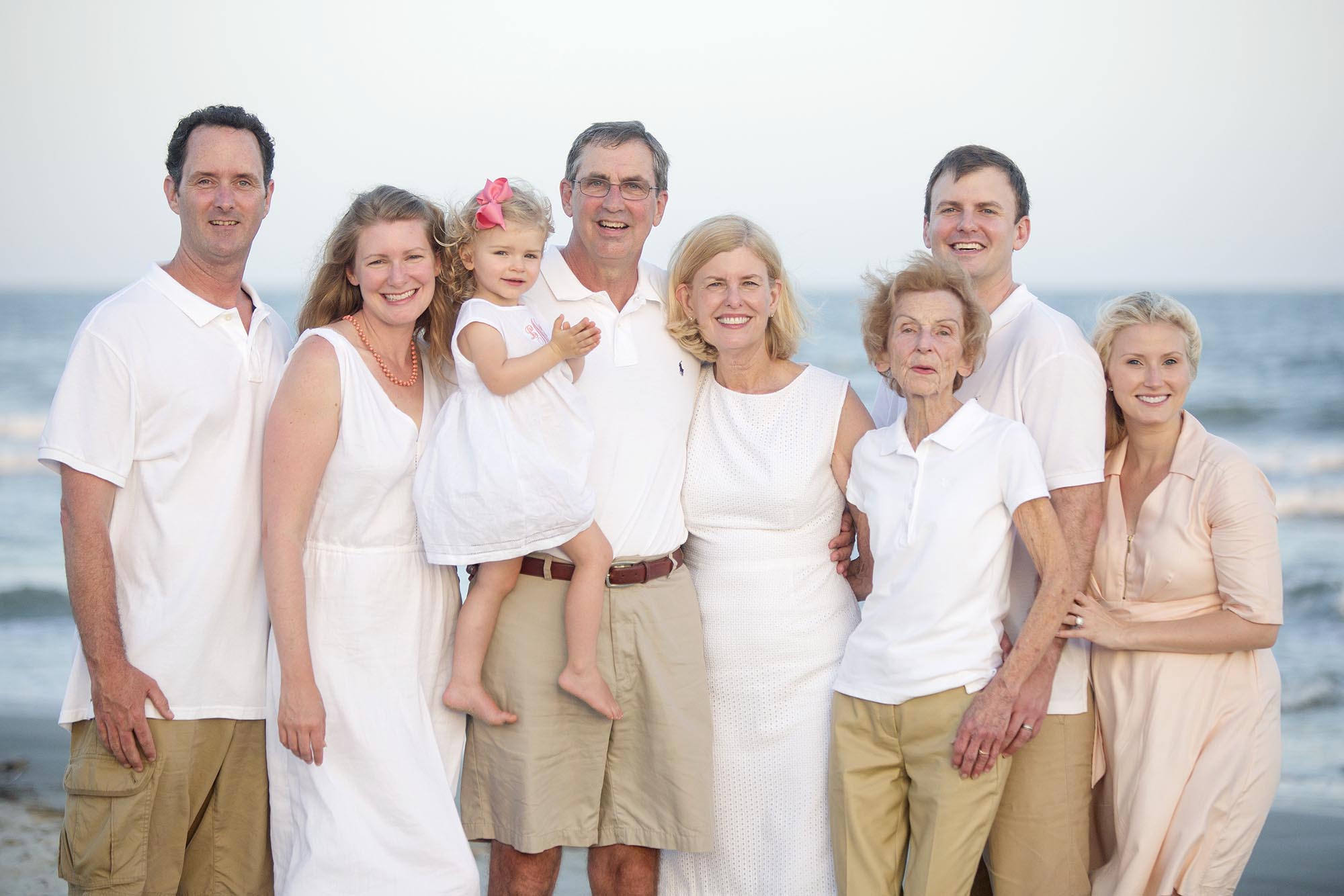 A family of eight posing for a photo at the beach.