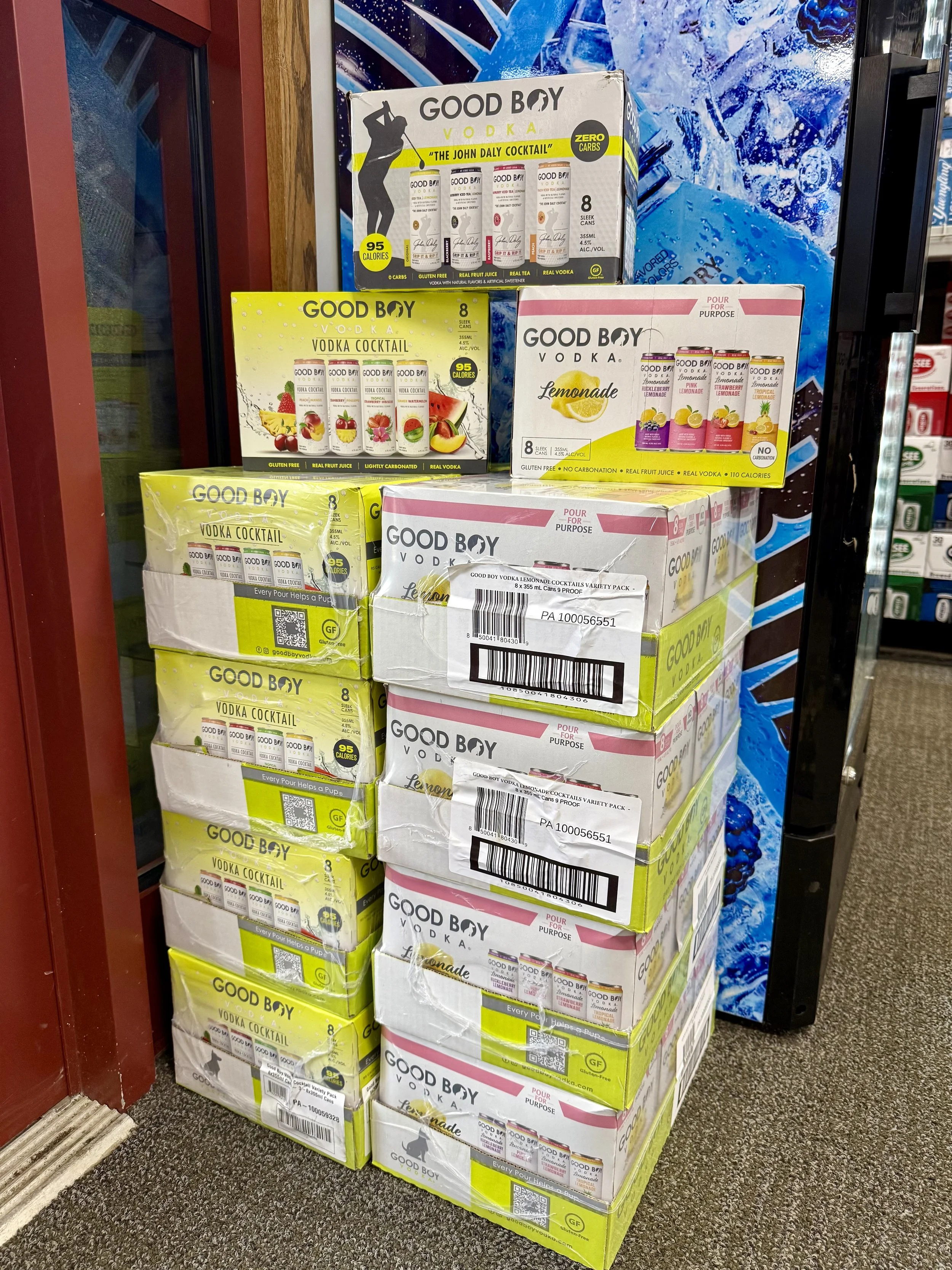 Stack of Ginger brand vodka boxes and cans on the floor in a store with a blue and purple mural in the background.