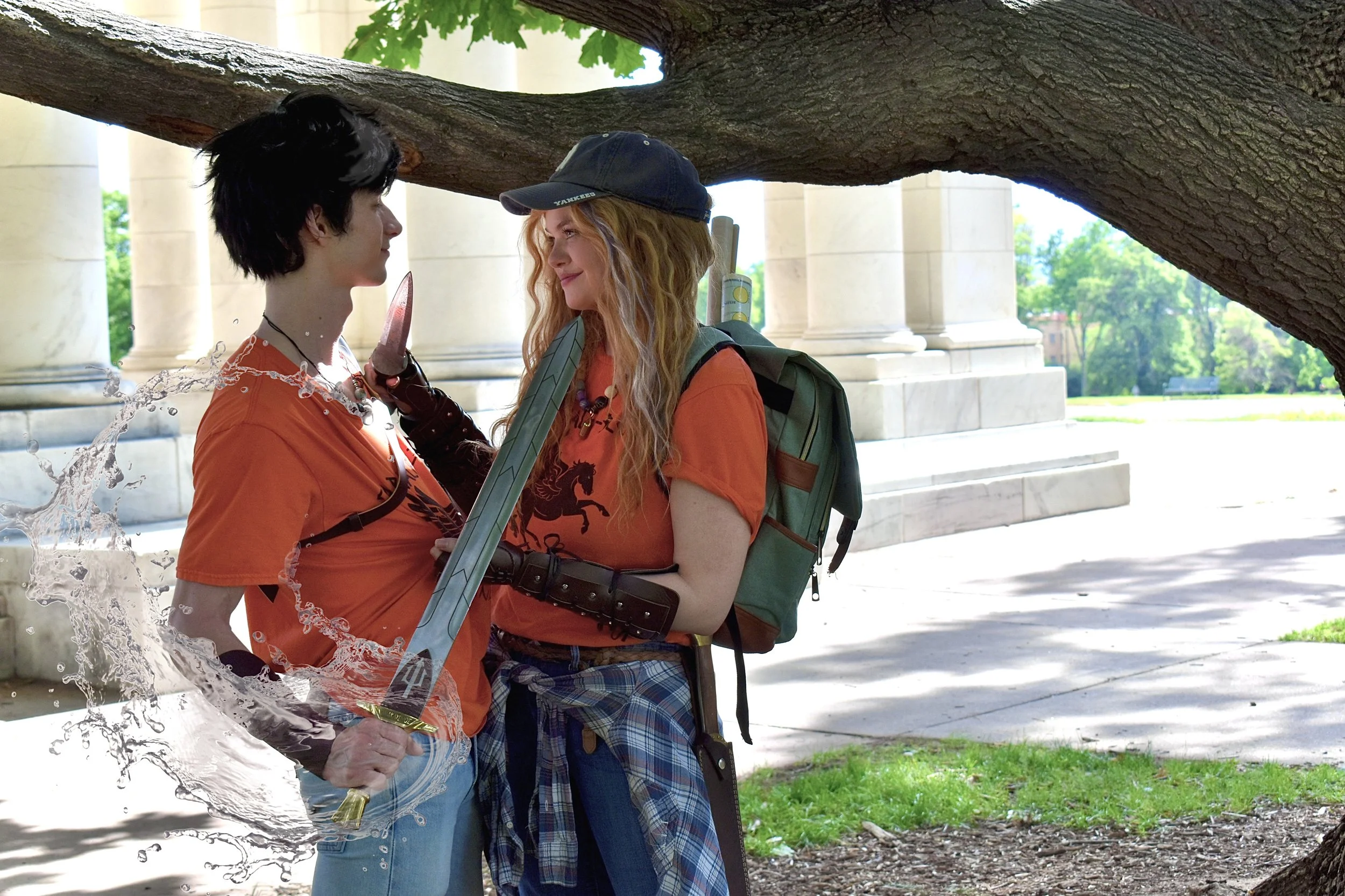 Imaginmatrix cosplaying Annabeth Chase in an orange camp half-blood t-shirt holds a knife to the throat of percy jackson, who in turn holds a sword (riptide) to her throat
