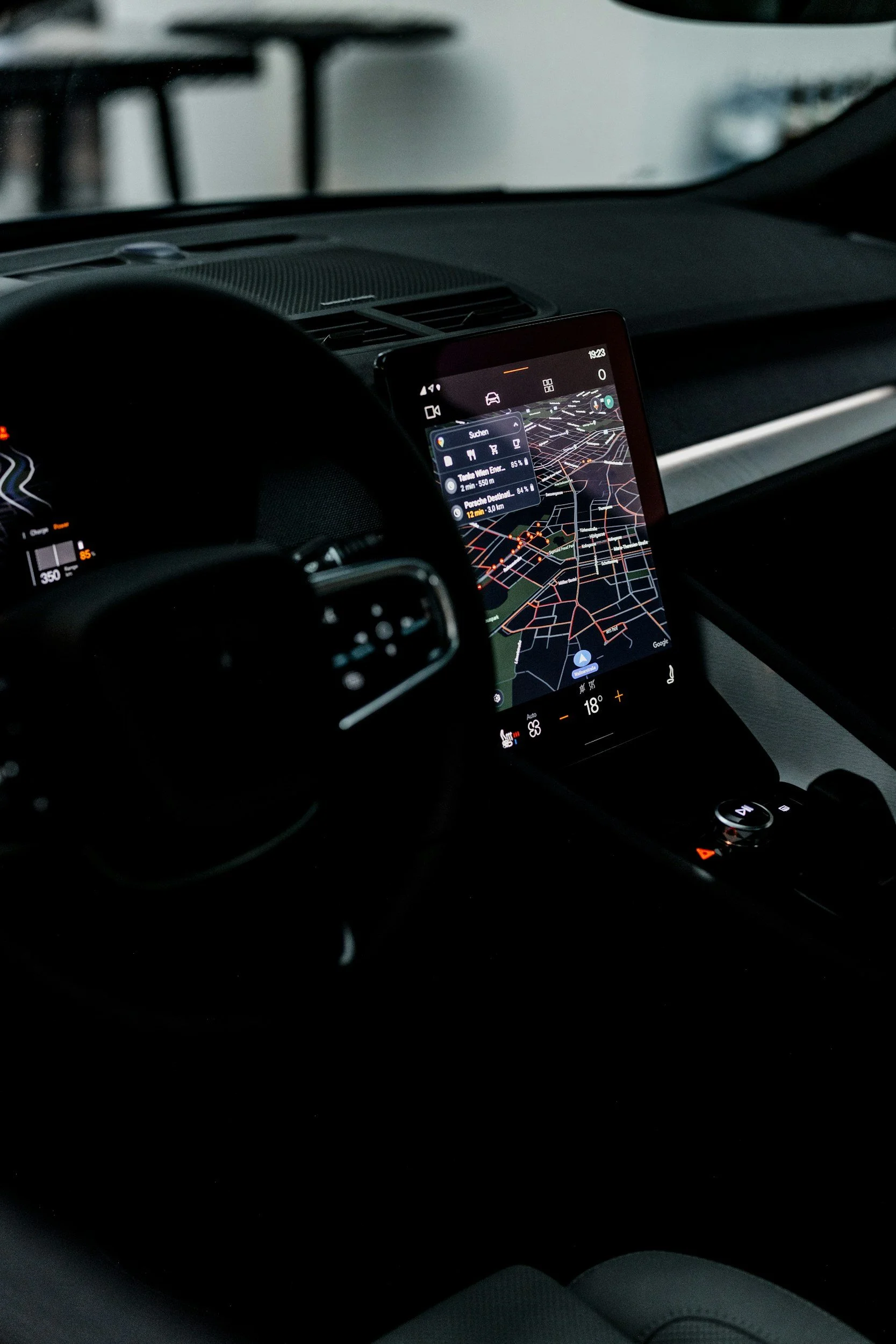 Close-up view of a car interior showing a digital dashboard and a smartphone displaying a navigation map.
