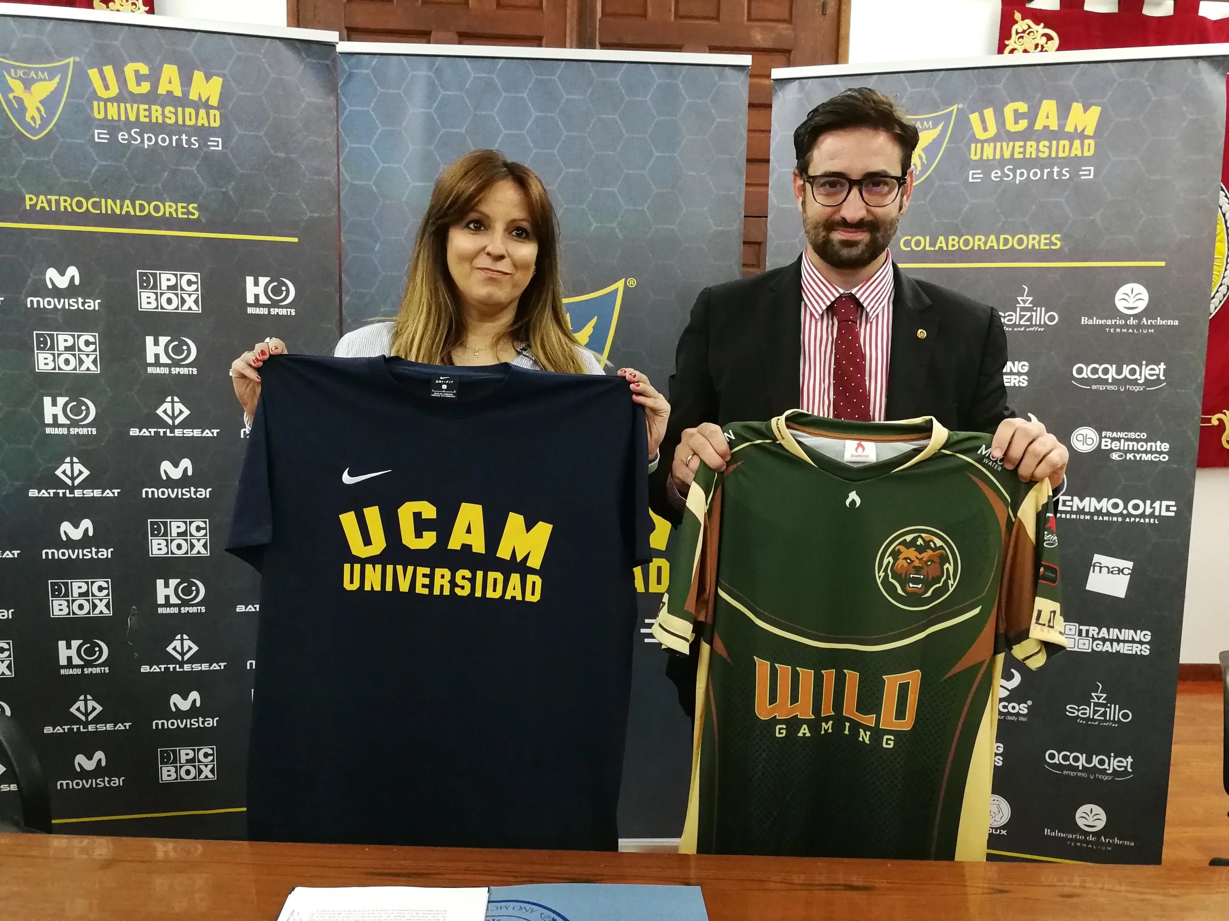 Blanca Chércoles, CEO de Wild Gaming y Samuel Mendoza, Director General de Infraestructuras y Desarrollo Digital de la UCAM, posan con las camisetas de UCAM y de Wild respectivamente. (Imagen: Wild Gaming)