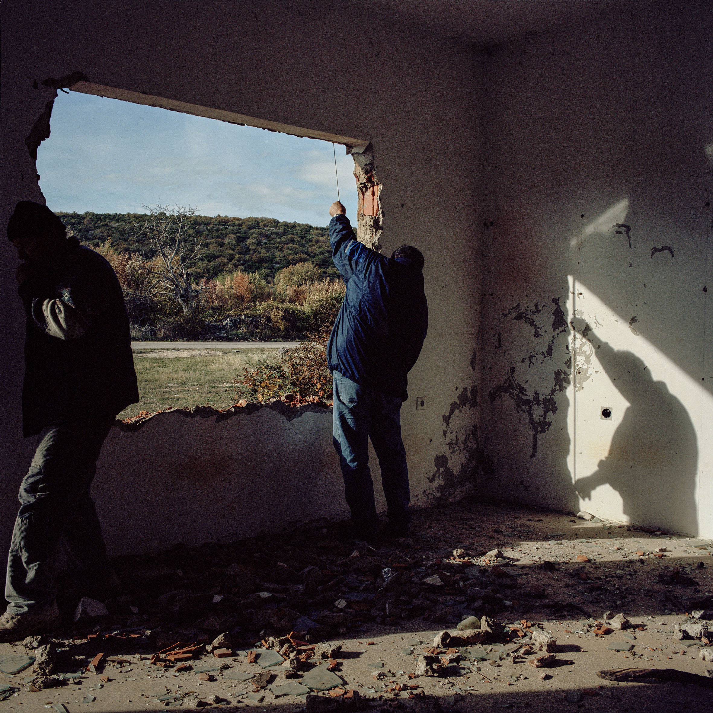  Workers from the Croatian Red Cross measure the window and door frames of Milan Calic’s destroyed home the day after he returned from 12 years of exile in Serbia. The fittings must be installed before his family can move into the house. Brgud, Croat