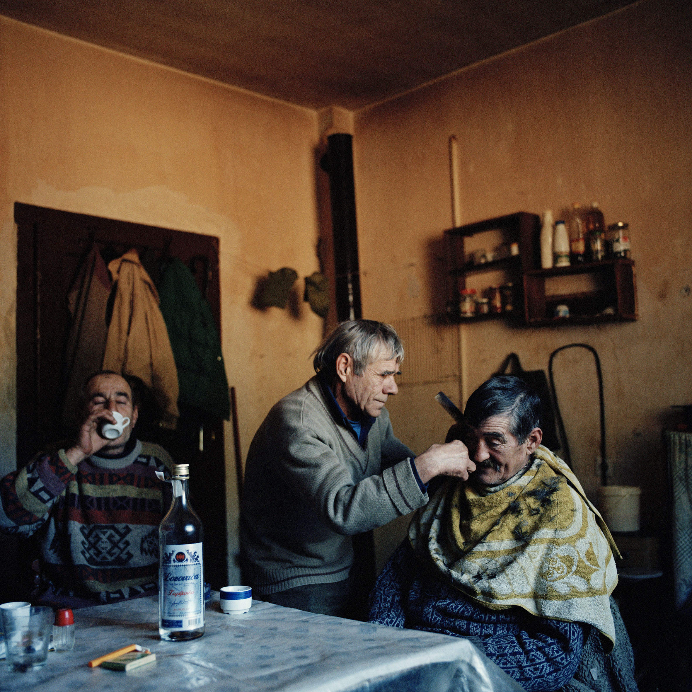  Sava Samardzija cuts the hair of his friend Slavolub Kristic while his brother Duro drinks brandy. The Samardzija brothers live as refugees in Rtanj collective centre in Serbia since fleeing their home in Croatia in 1995.   